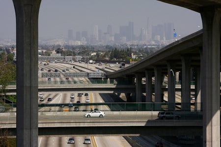 Traffic moves on Freeway with Los Angeles in distance.