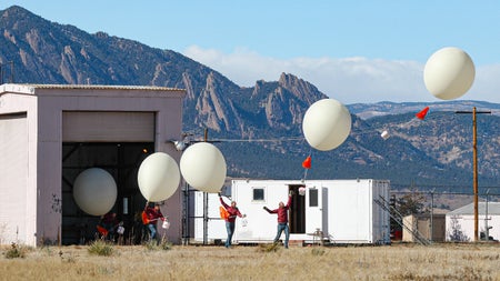 Composite image of a man releasing an ozone measurement balloon with mountains in the background.