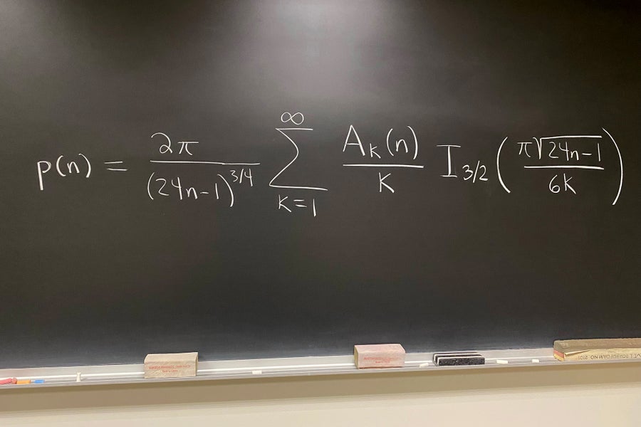 Math equation written in white on a black board.