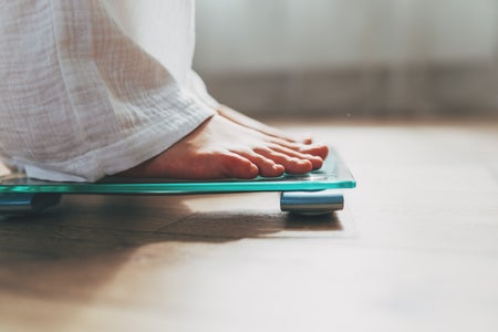 Barefoot feet showing white pant bottoms on scale.