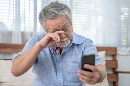 Elderly man rubbing eyes