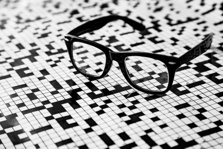 A pair of black glasses with a crossword puzzle background