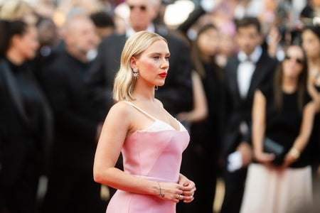 Scarlett Johansson in a pink dress on red carpet with crowd in background.