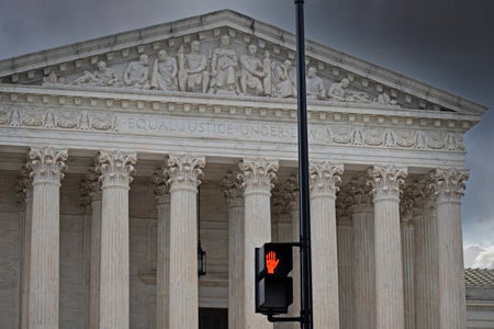 Supreme Court building with pedestrian street sign signaling "don't walk" in foreground.