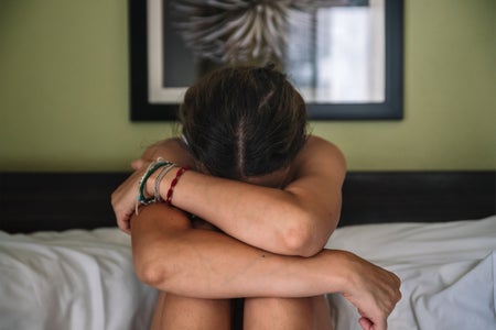 Young woman with depressive state sitting up in bed