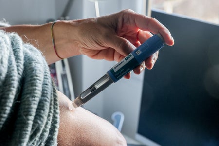 Female using Ozempic pen on her arm.