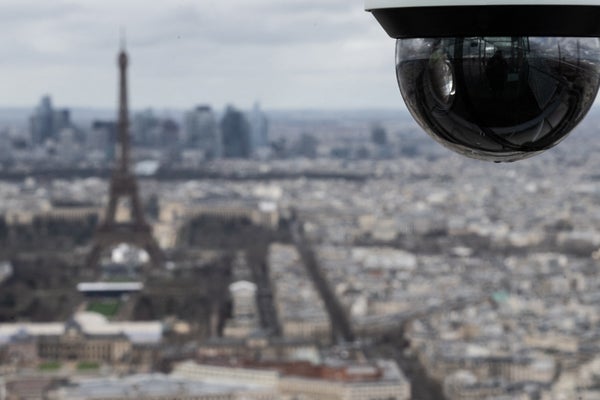 Photo from the rooftop of the Montparnasse Tower in Paris, shows a CCTV surveillance camera with the Eiffel Tower in the background.