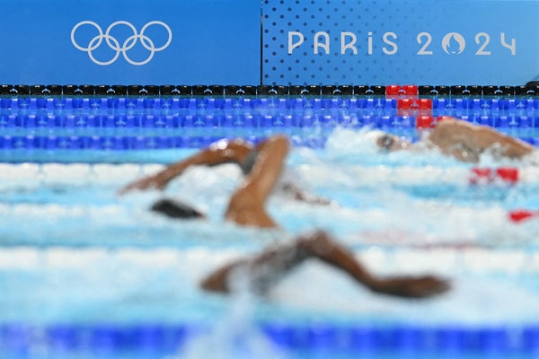 A photo shows the event logo and Olympic rings as swimmers compete in a heat of the men's 400m freestyle swimming event at the Paris 2024 Olympic Games at the Paris La Defense Arena