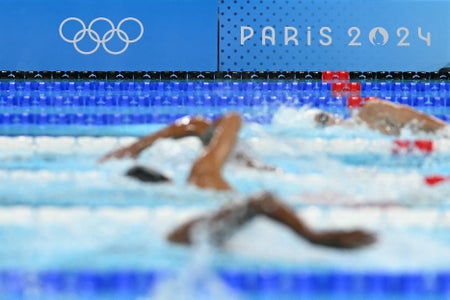 A photo shows the event logo and Olympic rings as swimmers compete in a heat of the men's 400m freestyle swimming event at the Paris 2024 Olympic Games at the Paris La Defense Arena