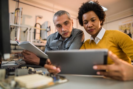 Two people looking down at a tablet.