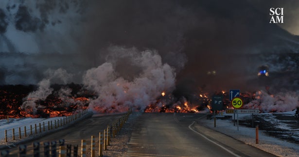 A view of a closed road with burning, smoking lava flowing over it in Iceland