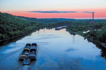 A tugboat pushes cargo on the Mississippi River at dawn.